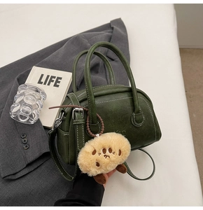Detail der vintage dunkelgrünen Bowlingtasche mit Plüsch-Anhänger auf grauem Anzughintergrund
