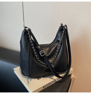 Detail of black hobo bag showing lychee leather texture and decorative silver chain