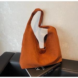 Gros plan du sac cabas en daim orange avec détail de bandoulière large nouée élégante