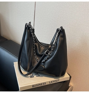 Close-up of black lychee grain leather dumpling bag with silver chain and dual straps