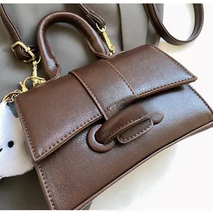 Detail of dark brown leather handbag with lychee texture and gold metal hardware