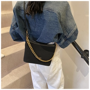 Detail of a black suede bucket bag with gold chain strap and fashion text on the side