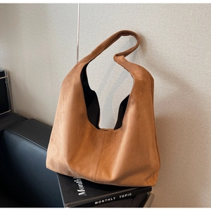 Gros plan détaillé sur le daim marron et les coutures verticales du grand sac cabas