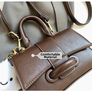 Detail of dark brown lychee texture leather bag with plush cloud charm and hand strap