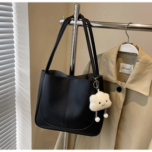 Detail of black pebbled leather tote bag with a white plush cloud charm on a hanger