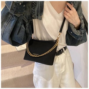 Detail of black leather crossbody bucket bag featuring gold chain and fashion lettering