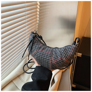 Dettaglio della borsa a mezzaluna in tweed pied-de-poule con tocchi arancioni e tracolla