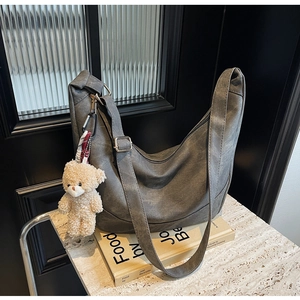 Detail der grauen Hobo-Tasche mit verstellbarem Gurt und süßem Plüschbären-Anhänger