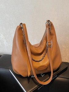 Brown grainy leather hobo bag with silver chain strap and shoulder strap on art books