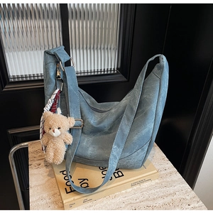 Detailansicht der blauen Canvas-Tasche mit Bären-Anhänger und kariertem Seidentuch