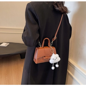 Brown leather crossbody bag shown on person with a cute plush cloud charm detail