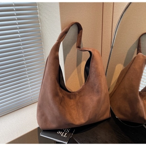 Detail view of a large brown suede tote bag featuring a minimalist vintage hobo silhouette