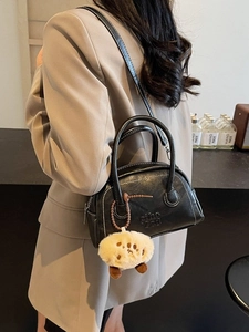 Schwarze Bowling-Tasche im Retro-Look mit weißen Nähten und Plüsch-Anhänger am Model