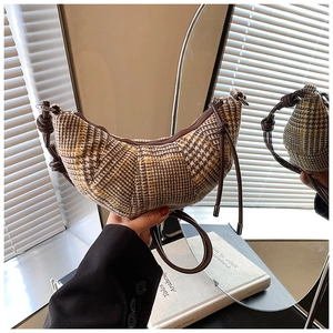 Dettaglio della borsa a mezzaluna a scacchi con tracolla in pelle e nodo decorativo