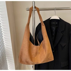 Détail du sac hobo en daim caramel avec bandoulière large montrant la texture douce et l'espace