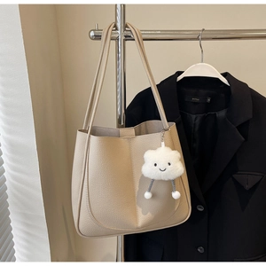Detailed view of beige tote bag with lychee texture and cute cloud plush pendant