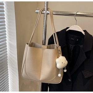 Detailed texture of beige pebbled leather tote bag with a white fluffy cloud pendant