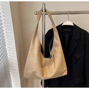 Détail d'un sac cabas minimaliste en daim kaki avec large bandoulière sur support métal