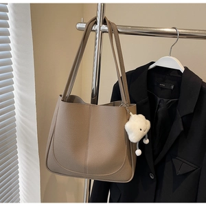 Detail of lychee textured leather tote with a cute plush cloud charm on the shoulder strap