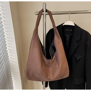 Détail d'un grand sac cabas en daim marron avec large bandoulière au style hobo minimaliste