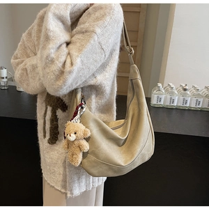 Detail der beigen Hobo-Tasche mit hochwertiger Textur und Plüschbär-Anhänger-Accessoire