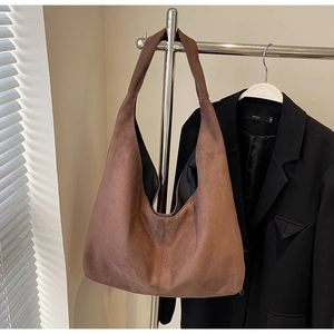 Détail d'un grand sac bandoulière en daim marron suspendu sur un support en métal chic