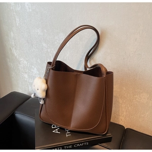 Brown litchi grain tote bag with plush cloud charm on a minimal studio background
