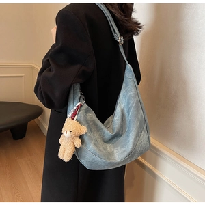 Detail der blauen Hobo-Tasche mit Retro-Ledertextur und süßem Plüschbären-Anhänger