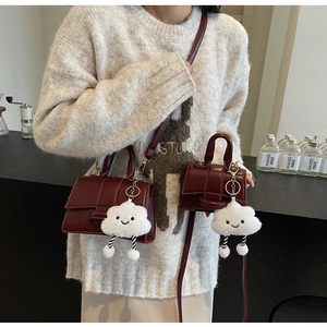 Detail view of burgundy leather handbags in two sizes with a cloud charm accessory