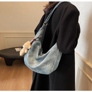Detail der blauen Denim Hobo-Tasche mit Teddybär-Anhänger und goldener Schnalle