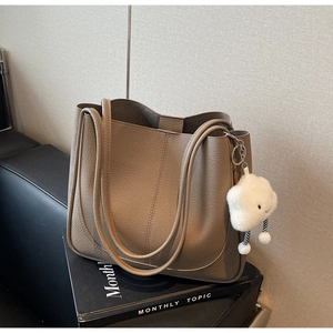 Detailed close-up of khaki pebbled leather tote bag with white fluffy cloud charm