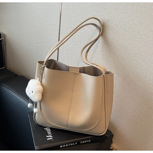 Detailed view of beige faux leather tote bag texture with white cloud charm accessory