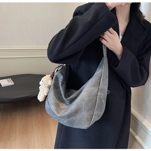 Detail der grauen matten Hobo-Tasche mit Reißverschluss und süßem Plüschbär-Anhänger