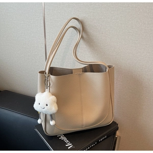 Detail of beige lychee grain leather tote bag with a cute white plush cloud charm