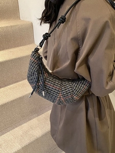 Elegante borsa a mezzaluna a quadri in lana, indossata a tracolla su una modella di stile