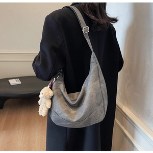 Detailansicht der grauen Hobo-Tasche mit Vintage-Textur und Bärenanhänger an der Schulter