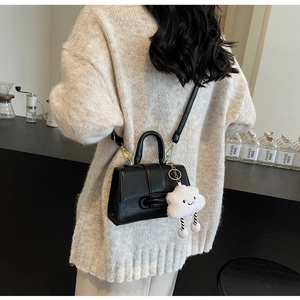 Detail of black leather crossbody bag featuring a cute white cloud plush pendant