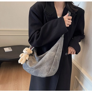 Nahaufnahme der grauen Hobo-Tasche mit Bärenanhänger und weicher Vintage-Textur