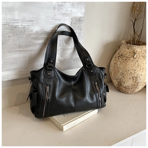 Detailansicht einer schwarzen Shopper-Tasche aus genarbtem Leder mit dekorativen Reißverschlüssen