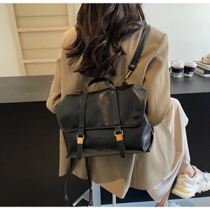 Dettaglio di uno zaino vintage in pelle PU nera con fibbie dorate e testo impresso
