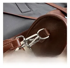 Detailed macro view of silver spring hook and brown lychee grain leather on handbag