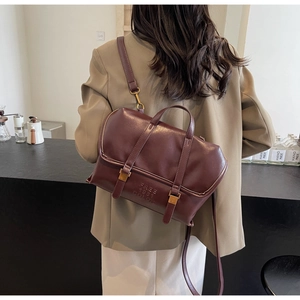 Dettaglio di uno zaino in ecopelle bordeaux con fibbie dorate e logo in rilievo