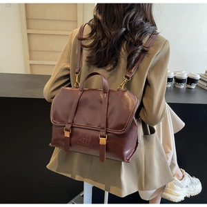 Dettaglio dello zaino vintage bordeaux in finta pelle con fibbia dorata e logo a rilievo