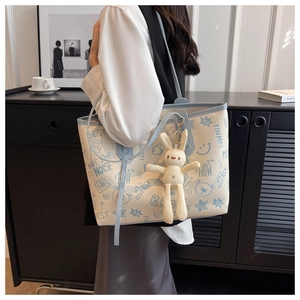 Dettaglio della borsa tote bianca con graffiti, manici blu e ciondolo a coniglietto