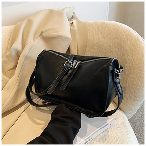 Detail of black cylinder shoulder bag featuring silver dual zippers and fine leather texture