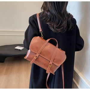 Zaino vintage in ecopelle marrone con fibbie metalliche e dettagli di scritte incise