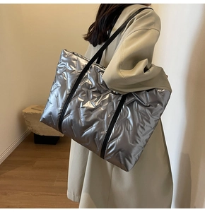 Détail du grand sac cabas argenté matelassé avec des lanières en cuir noir sur modèle
