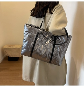 Détail du grand sac cabas argenté matelassé avec des anses noires sur l'épaule