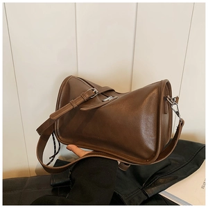 Detailed close-up of dark brown matte leather handbag featuring silver adjustable strap buckles