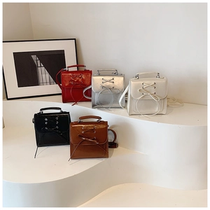 Five assorted mini patent leather handbags with decorative bows and detachable straps